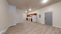 This single-floor unit offers a clean, functional layout designed for comfortable everyday living. The open-concept main area is expansive and airy, anchored by light wood-look luxury vinyl plank flooring that runs throughout the entire space, lending a cohesive and modern feel.

The kitchen is well-appointed with warm-toned medium wood cabinetry, white countertops, and a full suite of white appliances including an electric range, over-the-range microwave, dishwasher, and refrigerator. The galley-style configuration makes efficient use of the space while keeping the kitchen integrated with the main living area.

A structural column provides a subtle architectural division between the kitchen and living zones without interrupting the open flow. The living area is generously sized, offering flexibility for various furniture arrangements. Baseboard heating runs along the perimeter walls, and a wall-mounted mini-split unit provides climate control. Natural light enters through a window in the bedroom area, which also features continuity in the light flooring.

The bathroom is neatly finished with a white vanity, single sink, mirrored medicine cabinet, and brushed nickel hardware accents. Neutral wall tones throughout the unit create a calm, move-in-ready atmosphere that is both practical and inviting.