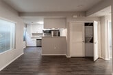 Located at 8389 Mount Hood Rd in Riverside, California, this single-story residence offers a well-designed, functional layout with modern finishes throughout. The open-concept living and dining area is anchored by rich wood-style flooring and neutral gray walls, creating a clean and cohesive aesthetic. A large window allows natural light to fill the entry and living space, enhancing the bright, airy feel of the interior.

The kitchen is a standout feature, equipped with crisp white shaker cabinetry, granite-style countertops, and a full suite of stainless steel appliances including a refrigerator, dishwasher, over-the-range microwave, and double-basin sink. A peninsula provides additional counter space and a natural divide between the kitchen and living area. An in-unit laundry closet is conveniently accessible from the main living space.

The bedrooms are carpeted for comfort, with neutral tones and ample natural light from windows with blinds. Each room offers closet space, including a walk-in style closet in the primary bedroom. The bathroom is well-appointed with white cabinetry, a granite-topped vanity, a large mirror, and a glass-enclosed walk-in shower, all set on matching wood-style flooring that ties the space together cohesively.