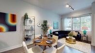 This well-appointed single-floor residence offers a thoughtfully designed layout that balances style and functionality throughout. The open-concept living and dining area serves as the heart of the home, featuring wood-style flooring, abundant natural light through large windows with sheer curtains, and track lighting overhead. The dining space accommodates a round wooden table with upholstered chairs, while the living area provides a comfortable setting with generous window views to the outdoors.

The kitchen is a standout feature, showcasing two-tone cabinetry with white upper cabinets and dark lower cabinets, light quartz countertops, stainless steel appliances, and a spacious peninsula island with seating — all illuminated by a sleek linear pendant light. A dedicated home office with bold accent wallpaper, built-in shelving, and a versatile sofa adds a creative and practical touch.

The bedroom is a serene retreat, highlighted by a dramatic dark accent wall, plush carpeting, large windows offering outdoor views, and a walk-in closet. The full bathroom features wood-style flooring, a bathtub and shower combination, a floating vanity, and black matte hardware accents throughout. The space presents a cohesive modern aesthetic from room to room.