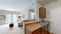 Located at 800 Ellington Cir in Gahanna, Ohio, this single-floor residence offers a well-designed, open-concept layout that seamlessly connects the main living areas. The living room is spacious and inviting, featuring plush carpeting, neutral-toned walls, and a sliding glass door that floods the space with natural light and provides access to an outdoor patio with views of the surrounding community.

The kitchen is efficiently designed in a galley style, equipped with warm wood cabinetry, granite-style countertops, a double-basin sink, and black appliances including a refrigerator, electric range, and over-the-range microwave. A peninsula with a pass-through opening connects the kitchen to the living area, enhancing the open flow of the floor plan. Wood-style flooring runs through the kitchen, adding a clean contrast to the carpeted living spaces.

The bedrooms are cozy and well-proportioned, each featuring soft carpeting, neutral walls, natural light from window treatments with blinds, and open closets with built-in shelving. Two bathrooms serve the residence, each finished with warm tile flooring, wood vanity cabinetry, granite-style countertops, and well-lit mirrors. One bathroom features a shower-tub combination, while the other includes a standalone shower. The overall ambiance is warm, functional, and move-in ready.