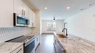 Located at 3812 W Montague Ave in North Charleston, SC, this well-appointed one-bedroom, one-bathroom unit offers a thoughtfully designed open-concept floor plan finished with contemporary details throughout. Wide-plank hardwood-style flooring flows continuously across the entire space, creating a cohesive and modern aesthetic.

The kitchen serves as a central hub, anchored by a large island with a striking granite countertop, an undermount sink, and a matte black faucet. White shaker-style cabinetry with black hardware lines the walls, complemented by a hexagonal tile backsplash and a full suite of stainless steel appliances, including a French door refrigerator, electric range, and over-the-range microwave. Recessed lighting and a ceiling fan keep the adjoining living area bright and comfortable, while large windows invite abundant natural light and outdoor views.

The bedroom is a calm, well-sized retreat with a ceiling fan, a large window with outdoor views, and direct access to a private outdoor area. A walk-in closet outfitted with wire shelving provides generous storage. The bathroom features a wide vanity topped with granite, white cabinetry, black fixtures, and a large framed mirror. The entrance and hallway connect all areas seamlessly, completing this efficient and modern layout.