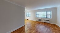 Located at 44 Hill St in Morristown, NJ, this 1-bedroom, 1-bathroom residence offers a well-appointed single-floor layout distinguished by warm parquet hardwood flooring that runs throughout every room. The spacious living area is bright and open, featuring elegant crown molding, clean white walls, and multiple windows with blinds that invite natural light and views of the surrounding greenery. Ceiling fans in key rooms provide year-round comfort alongside wall-mounted heating and cooling units. The dining area connects seamlessly to a compact, functional kitchen outfitted with stainless steel appliances, including a gas range and over-the-range microwave, as well as white cabinetry and ample counter space. The bedroom is generously sized, offering a ceiling fan, a large window, and a well-organized closet with a built-in rod and shelving. The bathroom has been tastefully renovated with large-format tile surround, a soaking tub with shower, a modern wood-toned vanity, and tile flooring. Crown molding in the main living spaces adds a classic architectural touch, while the consistent parquet flooring throughout ties the home together with warmth and character. The overall ambiance is clean, bright, and move-in ready.