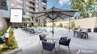 Located at 910 Willow Dr in Chapel Hill, NC, this outdoor patio is a thoughtfully designed communal space that delivers a resort-like experience. At its center sits a generously sized swimming pool with crystal-clear turquoise water, flanked by rows of modern chaise lounges ideal for sunbathing. The expansive pool deck is finished in a herringbone-patterned stone tile that extends throughout the courtyard, lending a polished and cohesive aesthetic to the space.

Shaded seating areas with large striped umbrellas provide comfortable spots for outdoor dining and socializing, while string lights overhead add a warm ambiance for evening gatherings. An outdoor kitchen equipped with grills offers a functional space for entertaining. The patio is framed by a contemporary multi-story building with large windows and private balconies, creating a well-defined and sheltered courtyard environment.

A standout feature is the enclosed cabana lounge, which showcases exposed wood beam ceilings, herringbone tile flooring, a rope-hung daybed, woven accent chairs, bold flamingo wall art, and a wall-mounted television — combining playful design with relaxed comfort. Lush greenery and mature trees at the perimeter soften the urban architecture, contributing to a lively yet tranquil outdoor retreat.