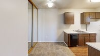 Located at 1326 E Cotati Ave in Rohnert Park, California, this one-bedroom, one-bathroom unit offers a practical and efficient single-floor layout. The galley-style kitchen is well-appointed with warm wood cabinetry lining both walls, white countertops, a stainless steel sink, and white appliances including a four-burner electric range and refrigerator, all set on wood-look flooring that adds a touch of warmth. The kitchen flows into a combined living and dining area, where soft carpet underfoot and a sliding glass door provide access to natural light and outdoor views. A ceiling fan adds comfort to the living space. The bedroom is a comfortably sized retreat featuring plush carpet, vertical blinds over a window with outdoor views, a textured ceiling, and two closets — one outfitted with mirrored sliding doors. The full bathroom is clean and functional, featuring a full tub and shower combo with white tile surround and chrome fixtures. Throughout the unit, neutral tones, textured ceilings, and consistent finishes create a cohesive and low-maintenance living environment suitable for individuals or couples seeking a well-organized space in a convenient Rohnert Park location.