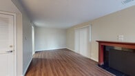 This single-floor space is thoughtfully laid out to maximize functionality across its key living areas. The living room serves as the centerpiece, offering generous open space finished with warm, medium-toned hardwood-style flooring that runs throughout. A standout feature is the classic fireplace framed by a rich wood surround and set on a dark tile hearth, adding character and a focal point to the room. A full-width vertical blind covers a sliding glass door, allowing natural light to filter in while providing privacy and access to the outdoors. Neutral beige walls and a textured ceiling keep the aesthetic clean and versatile.

The kitchen is designed in a galley configuration, featuring warm honey-toned cabinetry paired with light granite countertops that extend across both sides, offering ample prep and storage space. Light ceramic tile flooring, a stainless steel range, and an integrated sink complete the practical layout. A peninsula counter provides additional workspace.

The bathroom is finished in light neutral tones with ceramic tile flooring and includes a full soaking tub with a shower, a toilet, and clean white wall surrounds, offering a simple and functional design.