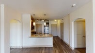 Located at 2255 Arkansas Ln in Grand Prairie, Texas, this single-floor residence offers a thoughtfully designed open-concept layout with modern finishes throughout. The kitchen serves as a central hub, featuring rich dark cabinetry, granite countertops, stainless steel appliances including a refrigerator, range, and built-in microwave, and a peninsula with an undermount sink and pendant lighting overhead. Durable hardwood-style flooring runs through the main living areas, creating a cohesive and easy-to-maintain aesthetic.

The living area is generously sized, bathed in natural light from large windows and a glass door that opens to a private balcony, complete with a ceiling fan for year-round comfort. Bedroom spaces are carpeted for warmth and also feature ceiling fans and natural light from well-placed windows.

The primary bathroom is particularly well-appointed, offering a double-sink vanity with granite countertops, dark cabinetry, a glass-enclosed walk-in shower with tile surround, and access to a walk-in closet. A secondary bathroom includes a single-sink vanity with matching granite finishes and a tiled tub-shower combination. Together, the rooms offer a clean, contemporary ambiance suited for comfortable everyday living.