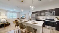 Located at 3111 Hayden Rd in Columbus, OH, this thoughtfully designed 2-bedroom, 2-bathroom residence offers a comfortable and functional single-floor layout. The open-concept kitchen, dining, and living area serves as the heart of the home, highlighted by a large quartz-topped kitchen island with bar seating and elegant globe pendant lights overhead. The kitchen features rich dark cabinetry, stainless steel appliances including a refrigerator, range, and microwave, complemented by light wood-style flooring that flows throughout the main living areas. Natural light enters through well-placed windows, creating a bright and welcoming ambiance in the living room, which offers generous space for lounging and entertaining. The spacious primary bedroom includes plush carpeting, ample room for a full furniture suite, and leads to a private en-suite bathroom and a walk-in closet. The second bedroom is versatile, also carpeted, and well-suited for use as a guest room or home office. Both bathrooms are finished with dark vanity cabinetry, white quartz countertops, and large mirrors. Additional highlights include four closets for abundant storage and a dedicated in-unit laundry area, rounding out this well-equipped residence.