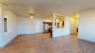 Located at 16511 East Sprague Avenue in Spokane Valley, WA, this single-floor unit offers a thoughtfully designed open-concept layout. The living area flows seamlessly into the kitchen, both finished with durable wood-style flooring that adds warmth throughout the common spaces. The kitchen is well-appointed with rich dark wood cabinetry, stainless steel appliances including a refrigerator, electric range, and microwave, complemented by light countertops. A peninsula with pendant lighting provides additional workspace and a pass-through connection to the living area. A dedicated pantry with open shelving offers generous storage. A central hallway connects the living spaces to two carpeted bedrooms, each featuring large windows that bring in natural light. The unit includes two bathrooms: one with a full tub/shower combo and wood-style flooring, and a second with tile flooring and a walk-in shower equipped with accessibility grab bars. Additional utility space houses the washer/dryer and water heater. A spacious walk-in closet with carpeted flooring provides ample storage. Baseboard heating is present throughout, ensuring year-round comfort in this clean, functional Spokane Valley residence.