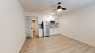 Located at 255 N Granada Ave in downtown Tucson, Arizona, this single-floor unit offers a clean, modern design with a bright and functional layout. Light-toned luxury vinyl plank flooring runs throughout, lending a cohesive and contemporary feel to the entire space.

The open living area is finished with crisp white walls and features a ceiling fan with integrated lighting, a wall-mounted HVAC unit, and a window dressed with horizontal blinds that allows natural light to fill the room. The space flows directly into a well-appointed kitchen, which is outfitted with white flat-front cabinetry, open upper shelving, a gray tile backsplash, light countertops, a stainless steel undermount sink, a built-in electric cooktop, a stainless steel microwave, and a full-size stainless steel refrigerator — providing a complete and efficient cooking environment.

A dedicated area off the main living space leads to a closet, offering practical storage. The bathroom is neatly appointed with a white vanity, a full bathtub with a sliding glass shower enclosure, a toilet, and coordinating chrome fixtures and accessories. The overall ambiance of the unit is fresh, minimal, and move-in ready, reflecting a thoughtfully updated interior.