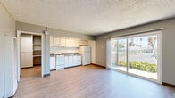 Located at 2 Marina Blvd in Pittsburg, California, this efficiently designed single-floor unit makes excellent use of its intimate footprint. Light gray luxury vinyl plank flooring runs throughout the space, lending a clean, cohesive look to every room.

The open living area is bright and airy, benefiting from a large sliding glass door that floods the space with natural light and provides direct access to a private balcony with outdoor views of surrounding greenery and palm trees. The textured ceiling adds subtle architectural character throughout. A wall-mounted HVAC unit ensures year-round comfort.

The kitchen is positioned along one wall and is outfitted with white cabinetry, a gas range, a refrigerator, and a double sink — providing all the essentials in a compact, organized layout.

The bathroom features a wide vanity with a gray countertop, under-sink cabinetry, a large mirror, and a full shower-tub combination, all finished with the same light vinyl flooring for a unified aesthetic.

A dedicated closet with a full-width hanging rod and built-in shelving provides practical storage. A hallway connects the main living areas, keeping the layout logical and functional. Additional unclassified rooms offer flexible space that can adapt to a variety of uses. Overall, the unit presents a tidy, move-in-ready environment with a neutral palette ideal for easy personalization.