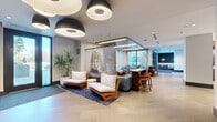 Located on Peachtree Street in the heart of Atlanta's Midtown neighborhood, this generously sized amenity floor offers a sophisticated blend of contemporary design and functional communal spaces. The welcoming entry lounge sets the tone with large-format tile flooring, striking oversized pendant light fixtures, and curated seating arrangements featuring warm wood-framed sofas and plush velvet chairs in rich blue tones. A bold large-scale art installation serves as a dramatic focal point near the entrance.

The central gathering area transitions seamlessly into an open-plan social space with wide-plank wood-look flooring, integrated kitchenette amenities, and multiple distinct seating vignettes suited for both casual lounging and focused work. A dedicated dining room offers an elegant marble-topped table with ample seating and floor-to-ceiling windows that frame lush street-level views of Peachtree Street.

A signature glass-railed hallway connects the various zones, offering open sightlines across the floor and showcasing a striking sculptural light installation below. Additional rooms feature herringbone-patterned accent walls, built-in display niches framed in warm wood, mounted displays, and bar-height seating. Throughout, recessed lighting, cove illumination, and carefully selected furnishings create a polished, welcoming ambiance.