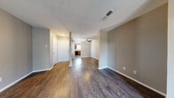 Located at 110 E Hawkins Pkwy in Longview, TX, this single-floor, 2-bedroom, 2-bathroom home offers a well-organized and functional layout. The living area features rich, dark hardwood-style flooring, neutral warm-toned walls, and a ceiling fan, creating a comfortable and inviting atmosphere. A sliding glass door with vertical blinds opens to an outdoor space, allowing natural light to fill the room. The combined dining and kitchen area is equipped with warm wood cabinetry, granite-style countertops, and black appliances including an electric range and refrigerator. Both bedrooms are carpeted for added comfort, each featuring closet access and windows that bring in natural light. The primary bedroom is generously sized with two separate doorways, providing access to additional closet space. Both bathrooms are finished with white tile tub-shower surrounds, wood-toned vanities, and hardwood-style flooring. The home also includes a dedicated laundry area, a hallway connecting the main spaces, and multiple closets throughout for ample storage. The textured ceilings and clean white trim throughout provide a classic, cohesive finish to this practical and comfortable Longview residence.