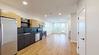 Located at 1414 4th Ave S in Nashville, TN, this thoughtfully designed one-bedroom, one-bathroom unit offers a modern aesthetic across a single, efficiently organized floor. The open-concept living area seamlessly combines the kitchen, dining, and living spaces, creating a bright and connected environment. Light wood-tone flooring runs throughout the main areas, complementing the clean white walls and recessed lighting overhead.

The kitchen is a standout feature, showcasing dark lower cabinetry paired with warm natural wood upper cabinets, dark tile backsplash, dark countertops, and a full suite of stainless steel appliances including a French door refrigerator, electric range, microwave, and dishwasher. A built-in shelf adds a contemporary touch near the entryway hallway.

The living area is bathed in natural light through multiple windows with adjustable blinds, offering views of the surrounding Nashville neighborhood. The bedroom features plush carpeting, two generously sized windows framing urban views, and a private door for added privacy. Two closets provide ample storage.

The bathroom is finished with white subway tile surrounding a full soaking tub and shower, black hardware accents, a dark vanity with a white countertop, and a backlit mirror. A dedicated laundry area and utility room round out this well-appointed Nashville residence.