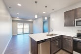 Located at 1920 Gregg Rd in Bellevue, Nebraska, this thoughtfully designed one-bedroom, one-bathroom residence offers a comfortable and functional single-floor layout. The open-concept living area seamlessly connects the kitchen, dining, and living spaces, creating an inviting atmosphere filled with natural light from a sliding glass door that leads to a private patio with outdoor views.

The kitchen is a standout feature, showcasing rich dark-toned cabinetry, crisp white countertops, a peninsula island with a double-basin sink, and a full suite of stainless steel appliances including a refrigerator, range, microwave, and dishwasher. Stylish pendant lighting above the island adds a modern touch. Wood-style flooring runs throughout the main living areas, contributing to a cohesive and contemporary feel.

The bedroom offers a comfortable retreat with two closets providing ample storage. The bathroom features a dark-cabineted vanity with a white countertop, a large mirror, and matching wood-style flooring. A dedicated laundry room includes a full-size washer and dryer with built-in shelving for added convenience. Recessed lighting throughout the unit completes the clean, modern aesthetic of this well-equipped residence.