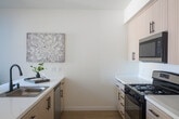 Located at 3519 Mercury Dr in Santa Maria, CA, this single-floor unit showcases a modern, minimalist aesthetic with clean lines and a neutral color palette carried consistently throughout the space. Light wood-tone flooring runs through the main living and kitchen areas, complementing the crisp white walls and creating a warm yet contemporary feel.

The open kitchen serves as a functional centerpiece, featuring light wood cabinetry with matte black hardware, white quartz countertops, and a kitchen island with an integrated sink. Stainless steel appliances — including a gas range, microwave, refrigerator, and dishwasher — complete the well-equipped setup. Track lighting above enhances visibility and adds a modern touch.

The living area benefits from natural light through windows that offer views of the surrounding greenery. A wall-mounted mini-split system provides efficient climate control throughout the unit. The entry door includes a sidelight panel, welcoming natural light into the space.

Additional rooms are finished with the same light hardwood flooring and bright white walls, offering clean, versatile spaces. The bathroom features a full tub-shower combination with striking matte black fixtures, adding a modern contrast to the white tile surround. Overall, the space presents a cohesive, contemporary design suited for comfortable everyday living.