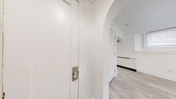 Located at 16 Chapel Road in Buffalo, NY, this thoughtfully updated one-bedroom, one-bathroom unit offers a clean and modern living experience. The single-floor layout is organized efficiently, connecting a kitchen, bedroom, bathroom, and hallway in a cohesive flow.

The kitchen is a standout feature, showcasing white shaker-style cabinetry with ample storage, light quartz countertops, and a full suite of stainless steel appliances including a refrigerator, range, and dishwasher. A range hood and undermount sink complete the functional setup. An elegant arched doorway connects the kitchen to the rest of the unit, adding a classic architectural touch.

The bedroom offers a comfortable and well-proportioned space, featuring light gray luxury vinyl plank flooring, crisp white walls, and crown molding that lends a refined character. A rich, warm-toned wood door adds a striking contrast to the bright interior.

The bathroom is finished with classic white subway tile surrounding a soaking bathtub, maintaining the unit's clean and timeless aesthetic.

Throughout the space, consistent light gray flooring, white walls, and crown molding create a cohesive, modern atmosphere. The neutral palette and updated finishes make this a move-in-ready unit ideal for comfortable everyday living.