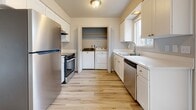 Located at 10267 SE 66th Ave in Portland, Oregon, this two-story residence offers a clean, updated interior with a cohesive neutral palette throughout. The main level features an open living area with light wood-style flooring, bright white walls, and a large front-facing window that draws in natural light and views of the surrounding neighborhood. A carpeted staircase with a sleek black metal railing connects the two floors, with a convenient under-stair closet providing extra storage. The living space flows into an adjacent room, offering flexible use options.

The kitchen is well-appointed with white shaker-style cabinetry, stainless steel appliances including a refrigerator, range, and dishwasher, light countertops, and a window above the sink. A dedicated laundry closet within the kitchen houses a full-size washer and dryer.

The upper level includes multiple bedrooms, each with light wood-style flooring, neutral walls, and windows overlooking greenery. One bedroom features dual closets with bi-fold doors and ample shelving, while another offers direct access to a full bathroom. The bathroom is finished with beige tile surrounding a soaking tub and shower, a white vanity, and wood-style flooring, creating a calm and functional space.
