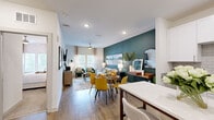 This thoughtfully designed 1-bedroom, 1-bathroom residence offers an efficient and stylish single-floor layout. The open-concept living and dining area is a standout feature, anchored by a bold teal accent wall that adds depth and character to the space. Wood-look flooring flows throughout the main living areas, complementing the bright, recessed lighting overhead. The living room offers a comfortable retreat with a ceiling fan and natural light from large windows dressed in sheer curtains.

The kitchen is well-appointed with crisp white shaker cabinetry, granite countertops, a subway tile backsplash, and a full suite of stainless steel appliances. A white quartz island provides additional prep space and casual seating.

The bedroom is a calm, carpeted retreat featuring soft neutral tones, ample space for a full furniture arrangement, a closet for storage, and window treatments for privacy. The bathroom is clean and functional, finished with white tile surrounds in the shower-tub combination and wood-look flooring. An in-unit laundry area with a top-load washer adds everyday convenience. Overall, the residence balances modern design with practical living.
