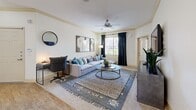 Located at 2505 E Williams Field Rd in Gilbert, AZ, this well-appointed one-bedroom, one-bathroom residence offers a thoughtfully designed single-level layout. The open-concept living and dining area is anchored by warm wood-look flooring, crown molding, and a ceiling fan, with large windows dressed in dark drapes that invite generous natural light. The kitchen is a standout feature, showcasing rich warm-toned cabinetry, granite-style countertops, black appliances, and a peninsula breakfast bar with pendant lighting — ideal for casual dining or entertaining. The bedroom is a comfortable retreat with plush carpeting, a ceiling fan, a large window with outdoor views, and ample closet space. The full bathroom features wood-look flooring, a soaking tub and shower combination, warm wood cabinetry, and clean white finishes throughout. A dedicated in-unit laundry area adds everyday convenience, while the private covered patio — with a cut-out window framing views of the surrounding greenery — offers a relaxing outdoor escape. A hallway connects all areas of the home efficiently, making the overall layout feel organized and functional.