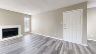 Located at 100 E Ridgeway Dr in Midlothian, TX, this single-floor, 2-bedroom, 1-bathroom home offers a well-organized layout with a comfortable, neutral aesthetic throughout. The living room serves as the heart of the home, featuring durable gray luxury vinyl plank flooring, a white-framed fireplace flanked by two windows that fill the space with natural light, and a textured ceiling. A front entry door with sidelights opens directly into this welcoming area. The kitchen runs in a galley-style configuration with crisp white cabinetry, light countertops, black appliances including a range and refrigerator, and matching LVP flooring, keeping the design cohesive. Both bedrooms are finished with plush carpet and ceiling fans, providing a warm and quiet retreat. The primary bedroom is generously sized and includes access to a walk-in closet equipped with built-in shelving on multiple walls, offering excellent storage capacity. The second bedroom features a large window that brings in ample natural light. The bathroom is clean and functional, with a full tub-shower combo finished in white tile, LVP flooring, and white cabinetry. Warm beige and greige tones carry consistently throughout the home, creating a cohesive and move-in-ready environment.