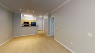 Located in the King Farm community of Rockville, MD, this apartment presents a thoughtfully designed single-floor layout that balances functionality and comfort. The open-concept kitchen features light wood cabinetry, dark countertops, black appliances including a gas range, microwave, and refrigerator, as well as neutral tile flooring that extends into the entryway and hallway. A breakfast bar separates the kitchen from the living area, creating a natural flow between spaces. The living room is generously proportioned, finished with plush carpeting, crown molding, and track lighting, with a ceiling fan adding comfort and a window offering views of the surrounding greenery. The bedroom is a calm, well-lit retreat with large windows framing lush tree views, plush carpet underfoot, and ample wall space for furnishings. The full bathroom is cleanly appointed with tile flooring, a warm wood vanity with a wide mirror, and a shower-tub combination. A hallway with louvered closet doors provides practical storage. Neutral wall tones throughout create a cohesive, move-in-ready atmosphere suited for a variety of personal styles.