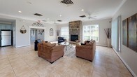 Located at 1201 Riverwalk Place in Frederick, Maryland, this single-floor space offers a generously proportioned, open-concept layout designed for comfort and functionality. The main lounge area is the centerpiece of the space, anchored by a floor-to-ceiling stacked stone fireplace that serves as a commanding architectural focal point. Large windows with vertical blinds line the walls, allowing abundant natural light to flood the interior and provide views of the surrounding greenery. Light-toned ceramic tile flooring extends throughout, lending a clean, cohesive aesthetic across the entire space. Ceiling fans with recessed lighting ensure year-round comfort. The lounge accommodates multiple seating arrangements, making it well-suited for both intimate gatherings and larger group activities. Adjacent to the main lounge, the fully equipped kitchen features soft blue-gray raised-panel cabinetry, granite countertops, stainless steel appliances including a range, dishwasher, microwave, and refrigerator, and a kitchen island with bar seating. A secondary lounge area with additional seating and access to the outdoors further extends the usability of the space. Together, these areas create a welcoming, versatile environment ideal for community gatherings and events.
