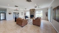 Located at 1201 Riverwalk Place in Frederick, Maryland, this single-floor space offers a generously proportioned, open-concept layout designed for comfort and functionality. The main lounge area is the centerpiece of the space, anchored by a floor-to-ceiling stacked stone fireplace that serves as a commanding architectural focal point. Large windows with vertical blinds line the walls, allowing abundant natural light to flood the interior and provide views of the surrounding greenery. Light-toned ceramic tile flooring extends throughout, lending a clean, cohesive aesthetic across the entire space. Ceiling fans with recessed lighting ensure year-round comfort. The lounge accommodates multiple seating arrangements, making it well-suited for both intimate gatherings and larger group activities. Adjacent to the main lounge, the fully equipped kitchen features soft blue-gray raised-panel cabinetry, granite countertops, stainless steel appliances including a range, dishwasher, microwave, and refrigerator, and a kitchen island with bar seating. A secondary lounge area with additional seating and access to the outdoors further extends the usability of the space. Together, these areas create a welcoming, versatile environment ideal for community gatherings and events.