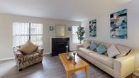 This single-floor, 2-bedroom, 2-bathroom residence offers a thoughtfully designed layout that balances comfort and functionality. The living room serves as the heart of the home, featuring a classic fireplace with a dark surround, wood-look vinyl flooring, and multiple windows dressed with vertical blinds that allow natural light to fill the space. The adjacent dining area includes a sliding glass door that opens to an outdoor view, enhancing the sense of openness.

The galley-style kitchen is both practical and stylish, equipped with dark cabinetry contrasting crisp white countertops, a white electric range, dishwasher, and refrigerator. A window above the counter brings in additional natural light, and a pass-through opening connects the kitchen to the dining area. Overhead flush lighting completes the space.

Both bedrooms are carpeted and comfortably sized, each featuring windows with vertical blinds that invite natural light. The primary bedroom benefits from dual windows, adding to its airy feel. The two bathrooms are finished with dark vanity cabinetry, light countertops, and wood-look flooring. One bathroom includes a shower/tub combination with a curtain rod, while the second features a vanity with a large mirror and a window for natural ventilation. Together, these spaces offer a cohesive, move-in-ready home.