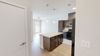 Located at 501 4th Ave SE in Cedar Rapids, Iowa, this thoughtfully designed one-bedroom, one-bathroom unit offers a clean, modern aesthetic across a single floor. Light wood-look flooring runs throughout, complementing the neutral palette of soft whites and warm grays that define the space.

The open-concept kitchen and living area serves as the heart of the unit. The kitchen is well-appointed with rich dark espresso cabinetry, granite-look countertops, black appliances including a range, microwave, and refrigerator, and a central island with pendant lighting above — ideal for casual dining or food prep. The adjacent living area benefits from natural light streaming through a glass-paneled exterior door and flanking window, with a ceiling fan adding comfort.

The bedroom is a comfortable, well-proportioned retreat featuring a ceiling fan, a window with exterior views, and direct access to both a walk-in closet with built-in shelving and the full bathroom. The bathroom features a wide vanity with dual sinks, a large mirror with overhead lighting, and dark cabinetry consistent with the kitchen's design language.

Throughout the unit, clean lines, bright walls, and consistent finishes create a cohesive, move-in-ready environment well-suited for modern living in downtown Cedar Rapids.