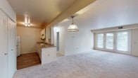 This single-floor residence offers a practical and well-organized layout designed to maximize functionality. The open-plan living and dining area is generously proportioned, featuring neutral wall-to-wall carpeting that adds warmth underfoot. A pendant light fixture hangs above the dining space, providing a focal point between the kitchen and living area. French doors lead from the living room to an outdoor balcony, filling the space with natural light and providing an outdoor connection.

The galley-style kitchen is efficiently designed with ample upper and lower cabinetry featuring wood-trimmed cream-colored doors. Granite-toned laminate countertops run along both sides, complemented by a double basin sink, white appliances including a coil-top range, refrigerator, and dishwasher, and wood-look flooring that extends throughout the cooking space.

The bedroom is a well-sized, carpeted room featuring a wide double louvered-door closet offering substantial storage. A decorative pendant light adds character to the space.

The bathroom is clean and functional, featuring wood-look flooring, a full tub-shower combination with a handheld showerhead, a toilet, and a vanity with granite-toned countertops and a large mirror above.