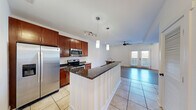 Located at 300 S Skyloft Dr in Asheville, NC, this well-appointed one-bedroom, one-bathroom residence offers a thoughtfully designed single-floor layout. The open-concept kitchen serves as a central hub, showcasing rich cherry wood cabinetry, dark granite countertops, a peninsula with pendant lighting, stainless steel appliances including a refrigerator, microwave, and electric range, and light ceramic tile flooring. The kitchen flows seamlessly into the living room, which features warm hardwood-style flooring, a ceiling fan, and a striking shiplap accent wall. French doors in the living area invite natural light and provide access to the outdoors. The bedroom is bright and airy, with light hardwood-style flooring, a ceiling fan, and a large window framing outdoor views. A dedicated closet offers convenient storage. The bathroom is finished with stone tile flooring, a granite-topped vanity with cherry wood cabinetry, a tall linen tower, and modern light fixtures. A separate utility room completes the layout. The clean, neutral palette and consistent finishes throughout give the space a cohesive, move-in-ready feel suited to Asheville living.