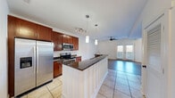 Located at 300 S Skyloft Dr in Asheville, NC, this well-appointed one-bedroom, one-bathroom residence offers a thoughtfully designed single-floor layout. The open-concept kitchen serves as a central hub, showcasing rich cherry wood cabinetry, dark granite countertops, a peninsula with pendant lighting, stainless steel appliances including a refrigerator, microwave, and electric range, and light ceramic tile flooring. The kitchen flows seamlessly into the living room, which features warm hardwood-style flooring, a ceiling fan, and a striking shiplap accent wall. French doors in the living area invite natural light and provide access to the outdoors. The bedroom is bright and airy, with light hardwood-style flooring, a ceiling fan, and a large window framing outdoor views. A dedicated closet offers convenient storage. The bathroom is finished with stone tile flooring, a granite-topped vanity with cherry wood cabinetry, a tall linen tower, and modern light fixtures. A separate utility room completes the layout. The clean, neutral palette and consistent finishes throughout give the space a cohesive, move-in-ready feel suited to Asheville living.