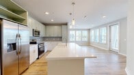 Located at 14455 N Main St in Jacksonville, FL, this well-appointed single-story home offers three bedrooms, three bathrooms, and a thoughtfully designed layout. The open-concept kitchen and living area serves as the heart of the home, featuring a large center island with a sleek white quartz countertop, pendant lighting, white shaker-style cabinetry, a decorative patterned tile backsplash, and stainless steel appliances including a refrigerator, range, and microwave. Natural light pours in through a generous bank of windows in the adjoining living area, creating a bright and welcoming atmosphere. Light wood-look flooring flows throughout the main living spaces and select bedrooms, while plush carpeting adds comfort to the remaining bedrooms. The spacious primary bedroom includes a ceiling fan and large windows with outdoor views, accompanied by an en suite bathroom boasting a dual-sink granite vanity, wood-framed mirrors, and a glass-enclosed shower. The additional bathrooms are equally refined, featuring granite-topped vanities and tiled tub-shower combinations. Each bedroom is paired with its own closet, with the primary closet offering generous wire shelving for organized storage. Neutral-toned walls and clean white trim throughout lend a cohesive, modern aesthetic to this move-in-ready home.