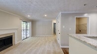 Located at Calibre Lake Pkwy SE in Smyrna, Georgia, this single-story, one-bedroom, one-bathroom residence offers a thoughtfully designed layout with quality finishes throughout. The open kitchen and living area serves as the heart of the home, where rich dark-wood cabinetry, granite countertops, a tile backsplash, and stainless steel appliances — including a gas range, microwave, and refrigerator — create a well-appointed cooking space. A peninsula with a granite overhang provides additional prep space and casual seating. The living room is warm and inviting, featuring a classic fireplace with a tile surround and white mantel, neutral carpet, crown molding, and a sliding glass door that opens to a private balcony with tree-lined views. Natural light fills the space through multiple windows dressed with shutters and blinds. The bedroom is a comfortable retreat with plush carpet, a ceiling fan, a window with an outdoor view, and a dedicated closet for ample storage. The full bathroom includes a tiled tub-and-shower combination. A utility room and hardwood-style flooring at the entry complete this efficiently designed, move-in-ready home.