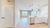 This thoughtfully designed single-floor residence offers three bedrooms and three bathrooms within a efficiently laid-out floor plan. The open-concept kitchen and living area serves as the heart of the unit, featuring sleek white cabinetry that extends to the ceiling for maximum storage, a quartz countertop peninsula with an undermount sink, and a full suite of stainless steel appliances including a refrigerator, range, and built-in microwave. Stylish black cone pendant lights hang above the peninsula, adding a modern accent to the bright, airy space. Light-toned hardwood flooring flows seamlessly throughout the entire unit, enhancing the sense of openness.

Each bedroom is well-proportioned and benefits from large windows that invite natural light and outdoor views of the surrounding neighborhood. The primary bedroom offers a comfortable footprint ideal for furnishing. All three bathrooms are finished with white vanities topped with quartz counters, polished chrome fixtures, and marble-style tile flooring. At least one bathroom features an elegant walk-in shower with floor-to-ceiling marble-patterned tile surround. Neutral warm-gray wall tones and clean white trim complete the contemporary aesthetic, creating a cohesive, move-in ready living environment.