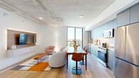 Located at 307 SW 5th St in Fort Lauderdale, FL, this modern one-bedroom, one-bathroom residence offers a thoughtfully designed layout across a single floor. The open-concept kitchen and living area serves as the heart of the home, showcasing striking exposed concrete ceilings that lend an industrial-chic aesthetic. Light wood flooring runs throughout, complementing the clean white walls and creating a warm, cohesive atmosphere. Floor-to-ceiling windows flood the space with natural light and frame sweeping views of the Fort Lauderdale skyline and surrounding cityscape, with direct access to a private balcony.

The kitchen is outfitted with sleek, matte blue-grey cabinetry, white quartz countertops, under-cabinet lighting, and a full suite of stainless steel appliances, including a gas range, dishwasher, and built-in microwave. A pantry and dedicated laundry area add practical convenience.

The bedroom is a serene retreat, featuring a large picture window with expansive city views, exposed concrete ceiling accents, and access to a dedicated closet. The bathroom is finished with a floating vanity, an LED-backlit mirror, and a glass-enclosed tile shower. Additional spaces include a hallway and utility room, rounding out this well-appointed urban residence.