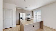 Located at 1933 S Acoma St in Denver's Baker neighborhood, this single-story residence showcases a clean, modern design with a cohesive neutral palette and light wood-look flooring throughout. The open-concept kitchen is a standout feature, equipped with flat-front cabinetry in a warm wood-grain finish, a spacious center island with an integrated sink and light quartz countertops, and a full suite of stainless steel appliances including a side-by-side refrigerator with ice maker, a built-in microwave, and an electric range. A bright window with horizontal blinds allows natural light to fill the space. The layout flows seamlessly from the kitchen into the living areas, which benefit from multiple large windows that invite abundant natural light and views of the surrounding neighborhood. The bedrooms are well-proportioned, each featuring light wood flooring, generous windows with blinds, and clean white walls — one bedroom includes a ceiling fan. The bathroom features marble-look tile flooring, a wood-tone vanity cabinet, and direct access to a walk-in closet. The overall design emphasizes minimalism and functionality, creating a bright and inviting environment throughout.