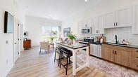 Located at 1150 N Price Rd in Saint Louis, MO, this one-bedroom, one-bathroom unit offers a thoughtfully designed single-floor layout. The open-concept kitchen and living area is a central highlight, featuring white shaker cabinetry, warm wood-toned lower cabinets, dark stone countertops, a classic subway tile backsplash, and stainless steel appliances. A kitchen island with a dark countertop provides additional prep space and casual seating. Light wood-style flooring runs throughout the main living areas, enhancing the bright, airy atmosphere. Large windows in both the living area and bedroom invite generous natural light and offer outdoor views. The bedroom is a comfortable retreat with plush carpeting, tall windows with floor-length curtains, and direct access to a dedicated closet. The bathroom features a wood-finish vanity with dark stone countertops, a large mirror, and modern pendant lighting, with light wood-style flooring continuing the cohesive design language. The unit's clean white walls and contemporary finishes create a modern, welcoming ambiance throughout.