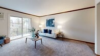 Located in Wayzata, MN, this well-designed two-bedroom, two-bathroom residence offers a comfortable and functional single-floor layout. The entryway opens through a hallway with hardwood-style flooring that connects seamlessly to the main living areas. The living room is bright and welcoming, featuring plush carpeting, warm crown molding with wood accents, and a sliding glass door that leads to a private balcony overlooking a landscaped green space with mature trees. The kitchen features warm wood cabinetry, light granite-style countertops, and a full suite of appliances, including a range and dishwasher. The spacious primary bedroom includes its own dedicated bathroom, complete with a round mirror, blue vanity cabinetry, and white countertops. The second bedroom is well-sized and versatile, filled with natural light from a large window. A second full bathroom features classic white tile flooring, tiled walls, and a clean, neutral palette. Two closets provide ample storage throughout the residence. Carpeted bedrooms and living areas, combined with hardwood-style flooring in transitional spaces, create a cohesive and comfortable ambiance throughout this inviting Wayzata home.