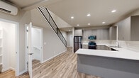 This thoughtfully designed three-story home offers 2 bedrooms and 4 bathrooms across a well-organized layout spanning three distinct levels. The ground floor houses a garage and utility room with a concrete floor, providing practical storage and parking. The main living level features an open-concept kitchen equipped with stainless steel appliances, gray shaker-style cabinetry, white quartz countertops, and a peninsula island ideal for casual dining or meal prep. Light wood-look flooring runs throughout the main level, complementing the neutral warm-gray wall tones. A striking open staircase with sleek black metal railings connects the floors, adding a contemporary architectural element. A mini-split unit provides climate control with efficiency. The upper floor hosts the two bedrooms, each finished with plush carpet flooring, recessed lighting, and windows that invite natural light and neighborhood views. The four bathrooms are clean and modern, featuring gray vanities with white countertops, tile flooring, and windows for ventilation. Two closets and a hallway round out the upper level. Throughout the home, the consistent use of neutral tones, modern fixtures, and quality finishes creates a cohesive, move-in-ready living environment.