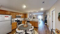 This well-appointed single-floor home in Fort Wayne, Indiana offers a smart, functional layout across a generously sized floor plan. The open-concept kitchen and living room serve as the heart of the home, where warm honey-toned cabinetry, granite-style countertops, and stainless steel appliances — including a refrigerator, electric range, and microwave — create an inviting culinary space. Pendant lighting accents the kitchen peninsula, while hardwood-style flooring flows throughout the main living areas, adding warmth and continuity.

The dining room provides a defined yet connected space for meals, complemented by a ceiling fan and natural light. A dedicated office with a window view offers a quiet retreat for work or study. The bedroom features plush carpeting, a ceiling fan, and a window with outdoor views, providing a comfortable, restful environment. Two full bathrooms serve the home, one featuring a walk-in shower, wood-toned cabinetry, and built-in shelving for added storage.

Practicality is well-addressed with four closets, a pantry, and an in-unit laundry area complete with overhead cabinetry. The spacious attached garage offers ample room for vehicles and storage. A private patio rounds out this home, extending the living space outdoors for relaxation and fresh air.