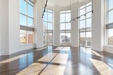 Located at 3400 Sharon Road in Charlotte's desirable 28211 zip code, this impressive two-story residence offers 4 bedrooms and 6 bathrooms across two thoughtfully designed floors. The main level commands attention with a dramatic double-height living area wrapped in floor-to-ceiling windows, flooding the space with abundant natural light and offering sweeping views of the surrounding Charlotte skyline. Rich hardwood flooring with a herringbone-inspired pattern anchors the grand main living area, while a sleek open staircase with modern metal railings connects to the upper level. The gourmet kitchen features crisp white shaker cabinetry, a classic subway tile backsplash, a quartz waterfall island, and stainless steel appliances — all complemented by a tray ceiling and large windows. A dedicated laundry room with full-size washer and dryer adds everyday convenience. The primary bedroom suite includes a generously sized walk-in closet with custom dark wood built-ins featuring adjustable shelving and integrated drawers. Bathrooms are elegantly appointed, highlighted by a soaking tub set within marble-style tile surrounds and gold-tone fixtures. The upper level, accessible via the open staircase, features carpeted bedrooms bathed in natural light with urban views. Throughout, the home maintains a clean, contemporary aesthetic with high ceilings, bright white walls, and refined finishes.