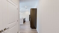 This thoughtfully designed single-story home offers two bedrooms, two bathrooms, and a functional layout that maximizes every square foot. The entrance opens toward an open-concept kitchen and living area, where light wood-look flooring flows seamlessly underfoot. The kitchen is a standout feature, centered around a granite-topped island with an undermount sink and stylish pendant lighting overhead. Rich, dark espresso cabinetry lines the walls alongside black stainless appliances, including a refrigerator, range, and built-in microwave. Adjacent open shelving adds a subtle architectural detail to the space. The bedrooms are bright and airy, each featuring ceiling fans, large windows that invite natural light, and wood-look flooring. The generously sized primary bedroom includes direct access to its own bathroom, which is appointed with a granite-topped vanity, tile flooring, and a glass-enclosed walk-in shower. Three closets throughout the home—including a spacious walk-in with wire shelving—provide ample storage. A dedicated laundry area adds everyday convenience. Neutral tones, clean white trim, and recessed lighting throughout give the home a fresh, modern aesthetic that is both functional and inviting.