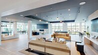 Located at 445 51st St in Wilmington, NC, this single-floor community clubhouse offers a generously sized, open-plan layout designed for social gathering and relaxation. The space is defined by its dramatic floor-to-ceiling black-framed windows, which flood the interior with natural light and provide sweeping outdoor views of the surrounding landscape.

Light wood-plank flooring runs throughout, complementing the contemporary coastal aesthetic. The main lounge area features multiple seating arrangements, including plush neutral sofas and accent chairs, anchored by a sleek linear fireplace set against a slate-toned feature wall. Pendant lighting and recessed fixtures add warmth and dimension across the open floor plan.

A dedicated games zone includes a full-sized pool table and casual seating, while a stylish wet bar with counter-height seating, stone tile backsplash, and pendant lighting serves as a natural social hub. The dining area showcases soaring double-height ceilings, large communal wood tables, and built-in banquette seating upholstered in mint green, framed by expansive windows on multiple sides. A kitchen prep area with teal cabinetry and a bold geometric tile floor adds a vibrant design accent. Throughout, the space balances modern architecture with inviting, resort-inspired furnishings.