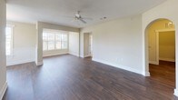 This single-floor residence at South Point offers a thoughtfully designed layout that balances comfort and functionality throughout. The main living area showcases rich, dark hardwood flooring that extends into the dining area, which is accented by a classic wainscoting detail and a pendant light fixture. A ceiling fan overhead and large windows dressed with horizontal blinds fill the space with natural light and views of the surrounding community. The living and dining areas flow seamlessly, creating an open and inviting atmosphere. The kitchen is well-equipped with warm wood cabinetry, granite-style countertops, and black appliances including an electric range and over-the-range microwave. The bedrooms feature plush neutral carpeting, ceiling fans, and windows with outdoor views, offering a calm and comfortable retreat. The primary bathroom includes a rich wood vanity with granite countertops, a large mirror, and a walk-in glass shower with dark hardwood-style flooring. A secondary bathroom mirrors the quality finishes, offering a full tub-shower combination, granite countertop vanity, and matching flooring. Neutral wall tones and clean white trim throughout tie the entire space together in a cohesive, understated aesthetic.