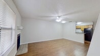 This two-story residence offers a practical and well-organized layout spread across two floors. The main level accommodates the primary living spaces, beginning with an entry area featuring hardwood-style flooring and a staircase leading to the upper level. The living room is a notable highlight, offering generous proportions with hardwood-style flooring, a textured ceiling, a ceiling fan with integrated lighting, and a fireplace with a classic white mantel—adding a warm, inviting focal point to the space. Natural light enters through windows fitted with horizontal blinds.

The galley-style kitchen is efficiently designed, featuring warm wood cabinetry, granite-style countertops, black appliances including a refrigerator and range, and vinyl flooring. A full bathroom on this level includes a wood-vanity with a wide mirror and hardwood-style flooring.

Upstairs, the bedroom provides a comfortable retreat finished with plush carpet and a sliding glass door fitted with vertical blinds, offering outdoor views and natural light. A second full bathroom on this level includes a tub/shower combination with white tile surround and additional cabinetry for storage. The neutral color palette throughout creates a clean, cohesive ambiance.