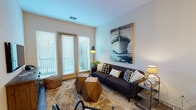 This single-floor residence offers a thoughtfully designed layout that balances modern aesthetics with comfortable living. The open-concept kitchen is a standout feature, showcasing a two-tone cabinet design with crisp white upper cabinets and rich wood-toned lower cabinets, complemented by a white subway tile backsplash and stainless steel appliances. A peninsula with a white countertop and seating for three pendant-lit bar stools makes the space ideal for casual dining and entertaining. Wood-style flooring flows throughout the main living areas, adding warmth and continuity.

The living room is bright and welcoming, benefiting from natural light that pours in through large windows and a glass-panel door leading to a private balcony. The space carries a nautical-inspired character, reinforced by curated décor and an expansive ship artwork anchoring the main wall.

The bedroom is a calm retreat, featuring carpet flooring, a generous window with outdoor views, and ample space for furniture. A rustic reclaimed-wood headboard adds distinctive character to the room, while a walk-in closet provides practical storage.

The bathroom is finished with granite countertops, a wood-toned vanity, a large mirror, and wood-style flooring, creating a clean and polished look throughout.