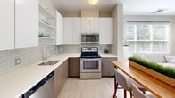 Located at 45 Nectaria Way in Manchester, New Hampshire, this well-designed two-bedroom, two-bathroom residence offers a clean, modern aesthetic throughout its single-level layout. The kitchen is a standout feature, equipped with stainless steel appliances including a full-size refrigerator, dishwasher, range, and microwave. Two-tone cabinetry pairs warm wood-finish lower cabinets with crisp white upper cabinets, complemented by a subway tile backsplash, white quartz countertops, and light hardwood-style flooring that lends the space a bright, contemporary feel. The living area continues the light-toned palette with hardwood-style floors and neutral walls, creating an inviting and versatile space. Both bedrooms are finished with plush carpet and soft neutral tones. The primary bedroom offers a comfortable layout with double closet doors and natural light from large windows with blinds. The second bedroom similarly benefits from ample natural light. The two bathrooms are finished with large-format tile flooring, wall-mounted vanities featuring white countertops and wood-tone cabinetry, and shower-tub combinations. A hallway and dedicated closet provide additional practical storage. Throughout, the residence maintains a cohesive, modern design with a calm, neutral color palette.