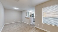 This two-floor residence offers a thoughtfully designed layout with a clean, modern aesthetic carried consistently throughout. The main living area features light-toned luxury vinyl plank flooring, neutral walls, and a ceiling fan, creating an open and airy atmosphere. A marble-surround fireplace serves as a focal point in the living room, adding a refined touch. Natural light filters in through slatted blinds on multiple windows.

The kitchen is positioned adjacent to the living and dining areas via a peninsula breakfast bar, providing both functionality and an open flow. It is equipped with stainless steel appliances including a full-size refrigerator and range, gray shaker-style cabinetry, and light stone countertops that lend a contemporary feel.

The dining area, also finished with vinyl plank flooring, connects seamlessly to the kitchen and benefits from its own ceiling fan and window.

Bedrooms are finished with plush carpeting and ceiling fans, offering a comfortable retreat. The primary bedroom includes access to a walk-in closet and a private en-suite bathroom. Bathrooms throughout feature wood-look tile flooring, white tile tub-shower surrounds, and light vanities with stone countertops, maintaining the home's cohesive, updated style.