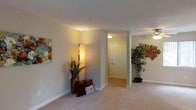 Located at 600 S Churton St in Hillsborough, North Carolina, this single-floor space offers a comfortable and inviting atmosphere with a clean, well-maintained interior design. The layout flows naturally from room to room, creating an open and connected feel throughout.

The main living area is finished with plush carpeting that adds warmth underfoot, while hard surface flooring is visible near the entryway, providing a practical and stylish transition zone. Smooth white walls and standard-height ceilings give the space a bright, airy quality, complemented by warm ambient lighting fixtures that cast a soft glow throughout.

The entryway is clearly defined, framed by a solid interior door and subtle architectural details including a structural column that subtly separates the entry corridor from the main living area. Decorative touches — including colorful wall art, tall floor lamps, and potted plants — add personality and visual interest to the space, suggesting a welcoming and livable environment.

The overall ambiance is calm and neutral, with a palette of soft beiges and whites that provide a versatile backdrop suitable for a variety of interior styles. The single-floor layout ensures ease of movement and accessibility, making the space both functional and comfortable for everyday living.